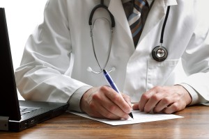 Doctor writing patient notes on a medical examination or prescription